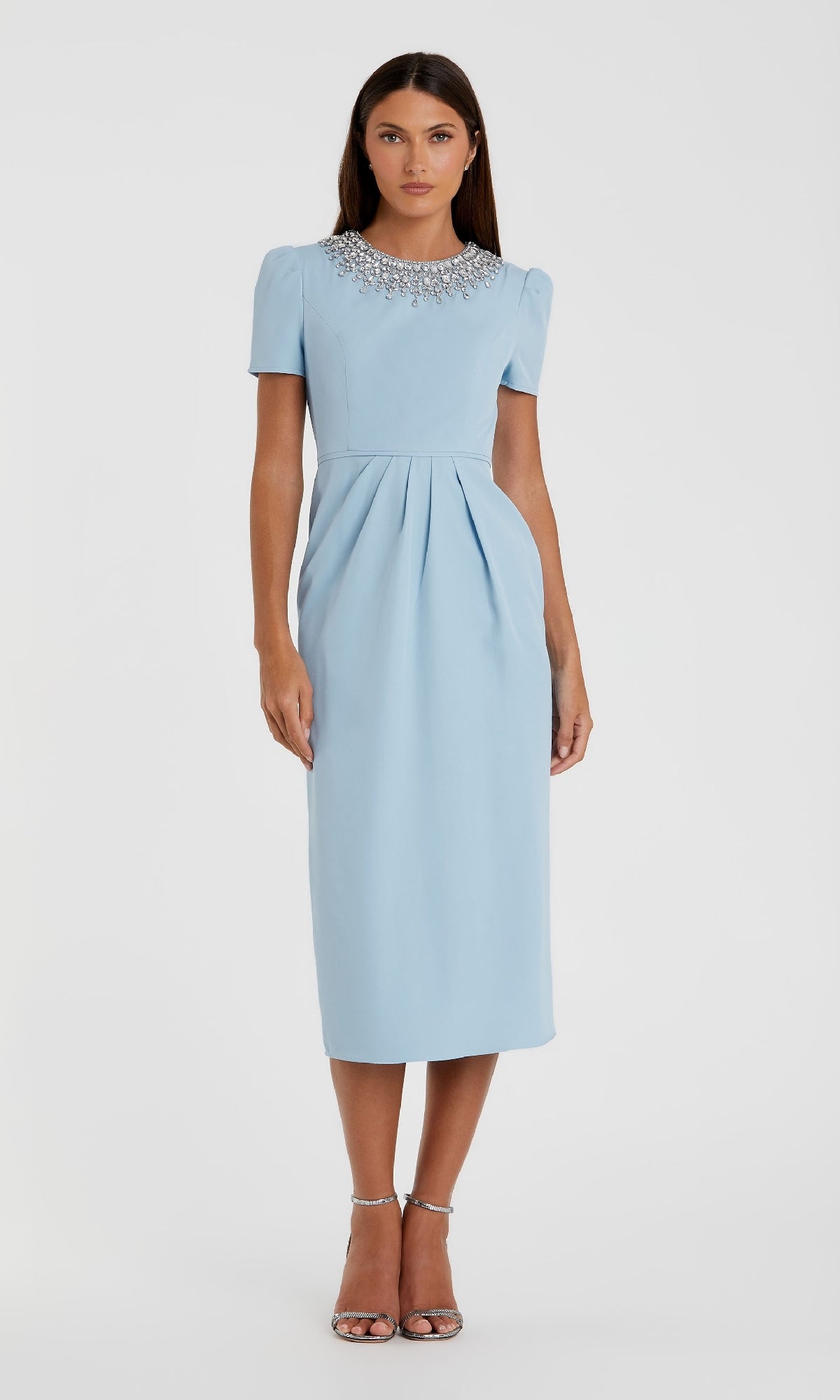 A woman wears the Mac Duggal 49606 short sleeve tea-length party dress in light blue with a beaded collar, paired with silver high-heeled sandals.